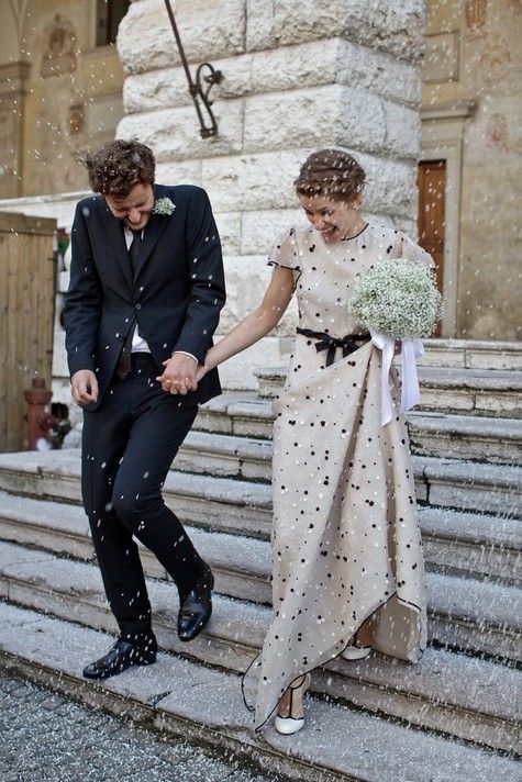 a neutral A-line wedding dress with white and black polka dots, white shoes with black detailing, a black sash for a timelessly elegant look