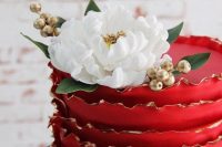 25 a red ruffle wedding cake with a gold rim, gold berries and a white bloom on top is a very cool and contrasting piece