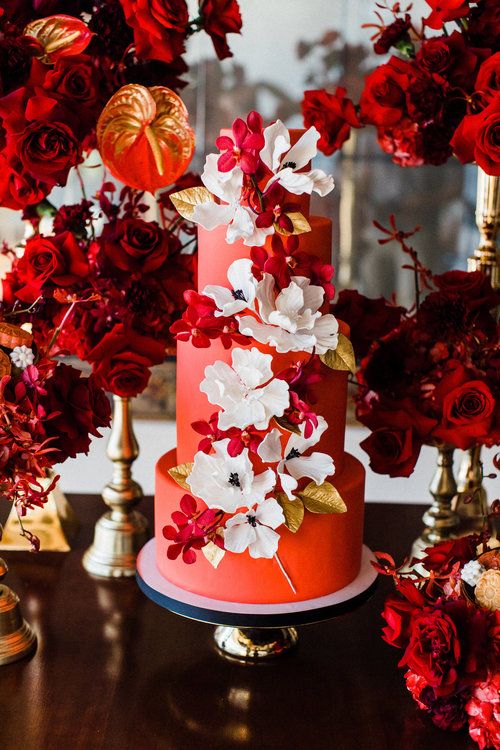 a red wedding cake with red and white blooms, with gold leaves is a fantastic idea for a colorful wedding, with an elegant combo of colors