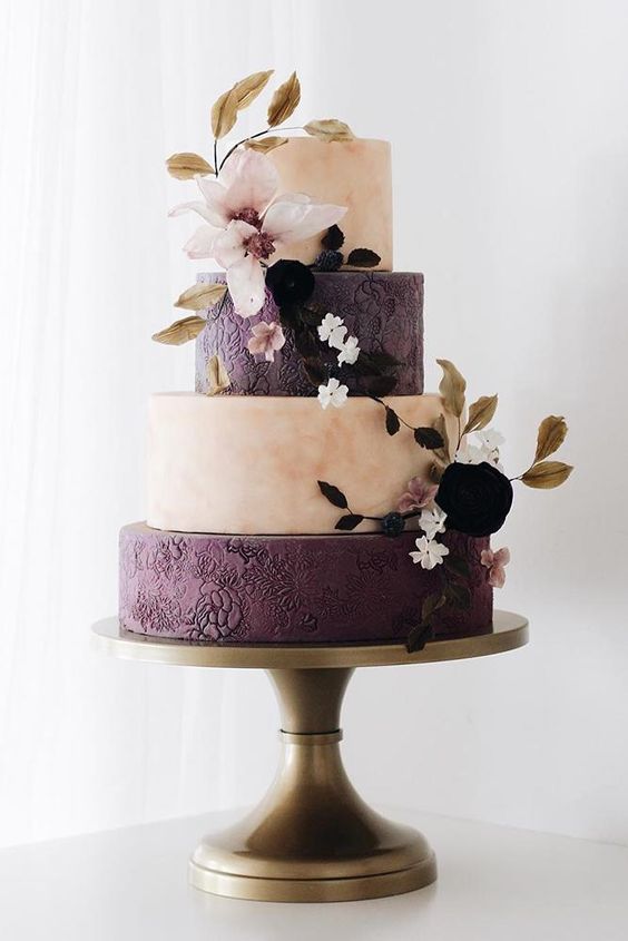 a sophisticated pink marble and deep purple flroal pattern wedding cake decorated with blush and deep purple blooms and dried leaves