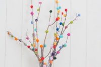 26 branches with small colorful pompoms attached compose a fun and bold wedding centerpiece and add color to the table