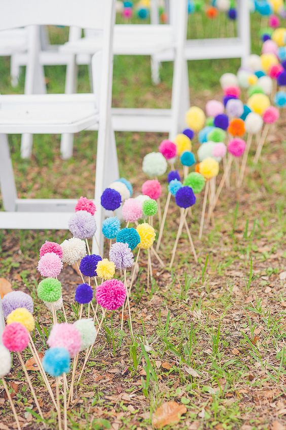 colorful pompoms on sticks are great to line up the aisle, you can DIY lots of them and brign a bold touch to the wedding aisle