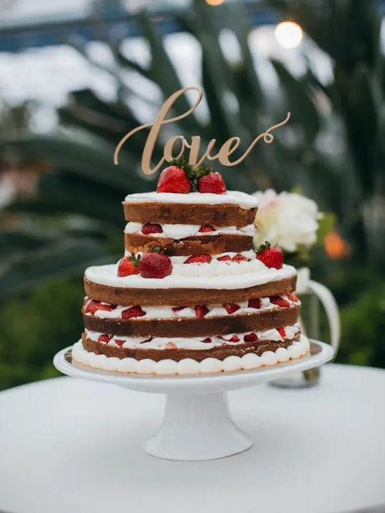 a naked wedding cake with strawberries and a gold LOVE topper is amazing and bold