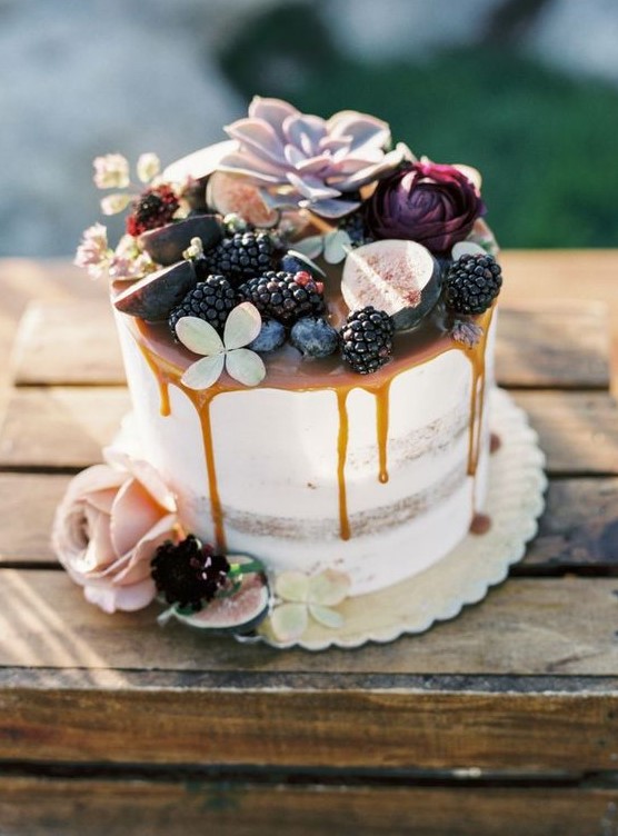 a semi naked fall wedding cake with caramel drizzle, blackberries, figs, blooms and succulents on top