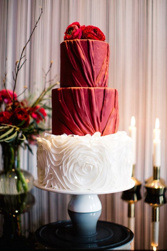 a sophisticated red wedding cake with textural pleated tiers and a white floral tier, with red blooms on top is a very chic idea