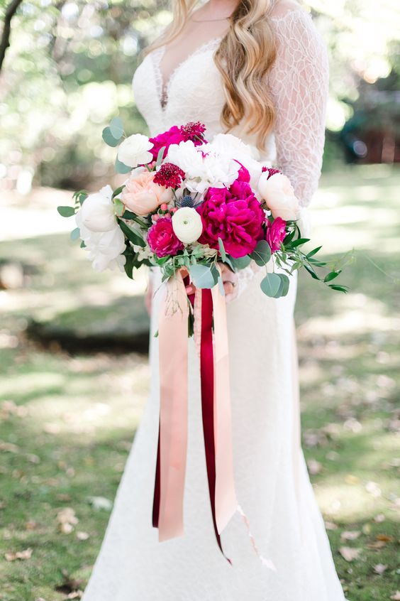a lovely wedding bouquet of hot pink peonies, white and blush ones, with long burgundy and blush ribbons is amazing