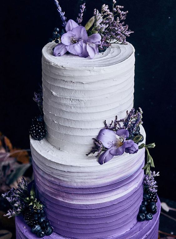an ombre white to purple wedding cake topped with purple blooms, with blackberries and blueberries is a bold and cool idea for your wedding