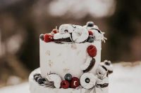 37 a chic white frosted wedding cake with gold leaf, white drip, berries and glazed donuts is amazing