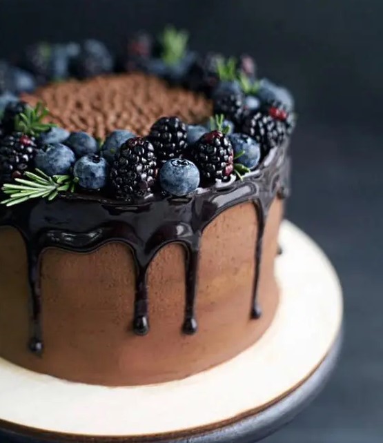 a chocolate wedding cake with chocolate drip, rosemary and fresh berries is a delicious dessert to serve for your guests