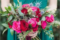 40 an emerald draped bridesmaid dress and a jewel-tone bouquet with hot pink, red blooms, greenery and thistles for a colorful fall wedding