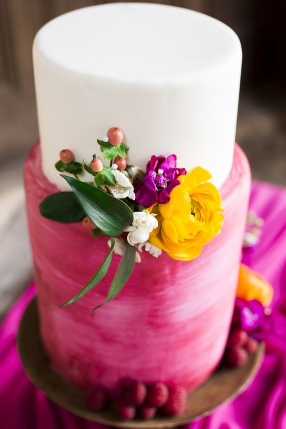 a bright wedding cake with a white and brushstroke hot pink wedding cake with berries, a yellow, a fuchsia and white bloom, greenery