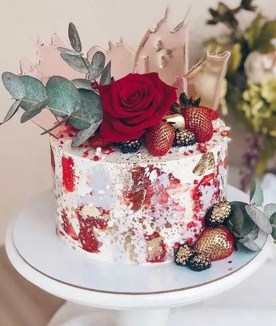 a unique wedding cake with red brushstrokes and gold leaf, gilded berries, a red rose, eucalyptus and pink sugar shards