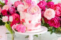 43 a pretty brushstroke wedding cake with pink and red touches, and lots of hot pink and light pink blooms and greenery around