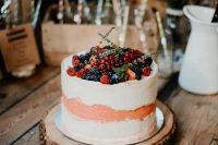 43 a white and peachy buttercream wedding cake topped with fresh berries and greenery is a lovely wedding dessert