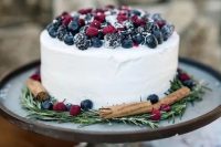 45 a white textural buttercream wedding cake topped with sugared berries, with cinnamon and rosemary is a cool rustic idea