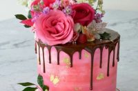 46 an ombre pink wedding cake with gold leaf, chocolate drip, hot pink and light pink blooms, greenery and berries