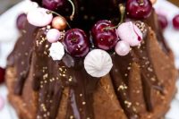 52 a chocolate bundt wedding cake with chocolate drip, gold leaf, fresh cherries, meringues and beads is a lovely and glam idea