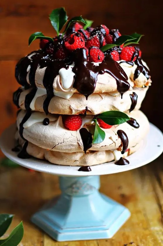 a pavlova cake with chocolate, raspberries, leaves and some drip is a delicious idea that everybody will enjoy