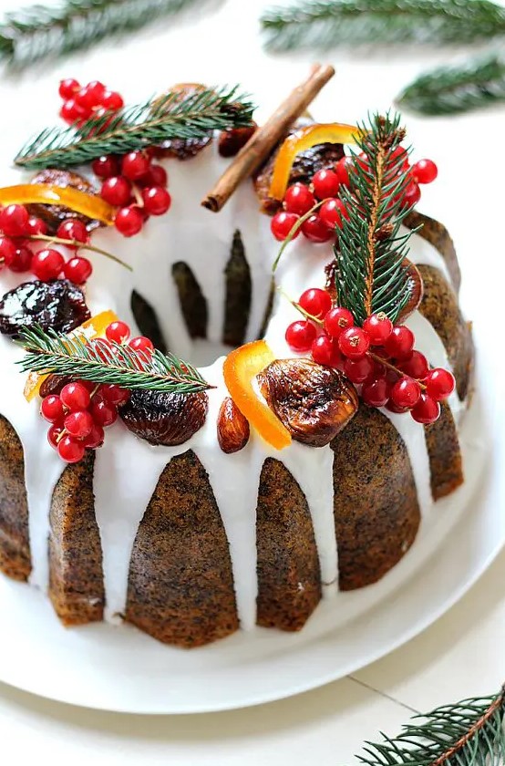 a poppy seed bundt wedding cake with white chocolate drip, cranberries, evergrenes, cinnamon and candied fruit