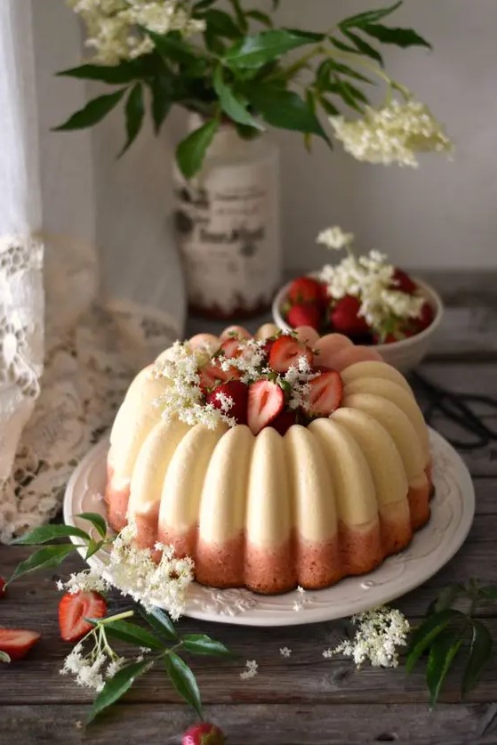 a white and pink bundt wedding cake with white blooms and fresh strawberries inside and on top is gorgeous