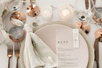 a beautiful modern wedding tablescape with neutral porcelain, copper glasses, neutral linens and candles is a very stylish idea