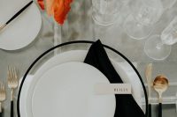a bold modern wedding tablescape with bold leaves and blush blooms, a clear table with no tablecloth, a blakc-rimmed charger and black cutlery