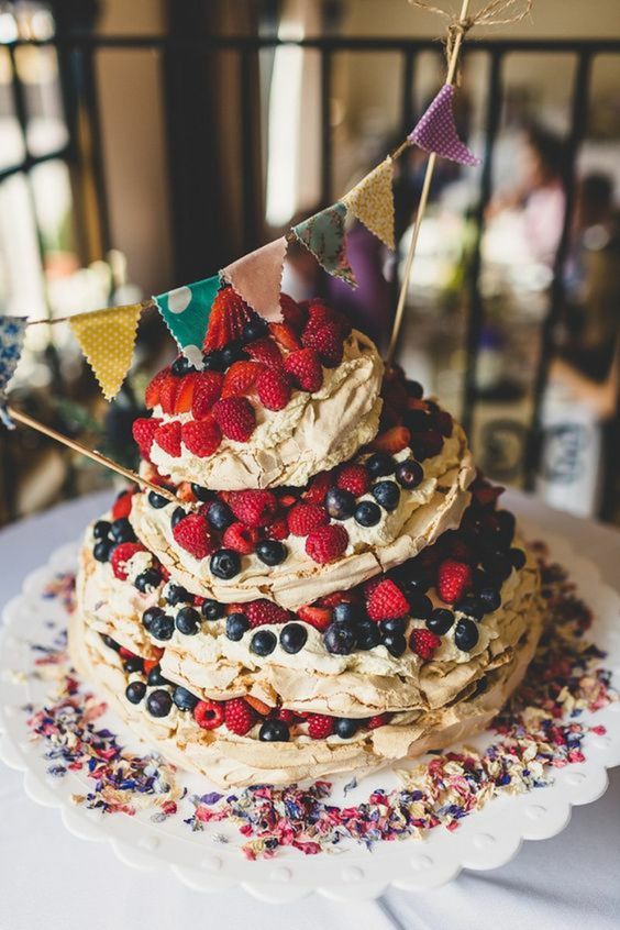 a bright and cool summer pavlova wedding cake with lots of fresh berries and a colorful banner topper is a lovely idea for a summer wedding