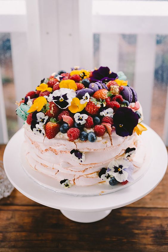 a bright meringue wedding cake wtih pansies and fresh berries is a gorgeous idea for a colorful summer wedding, it looks very inspiring