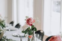 a cluster wedding centerpiece of silver bottles, white and orange ranunculus, a pink rose and some baby’s breath is amazing for a relaxed wedding