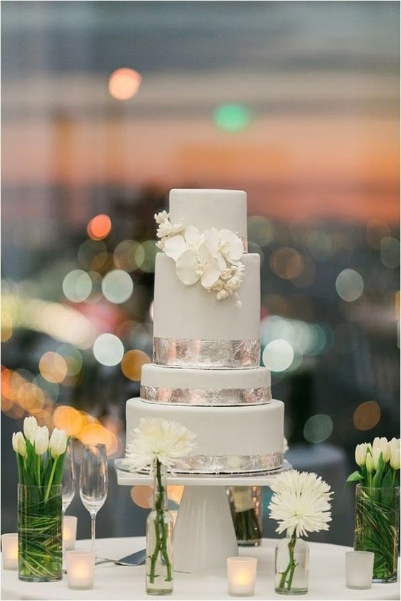 a dove grey wedding cake with silver leaf and white blooms is a beautiful and chic idea for a spring or summer wedding