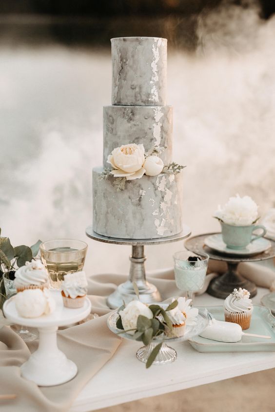 a grey watercolor wedding cake with silver leaf, blush blooms and pale greenery is a beautiful and stylish idea for a refined and delicate wedding