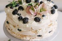 a meringue wedding cake topped with greenery and blackberries, with pink blooms is a gorgeous idea for a summer or fall wedding