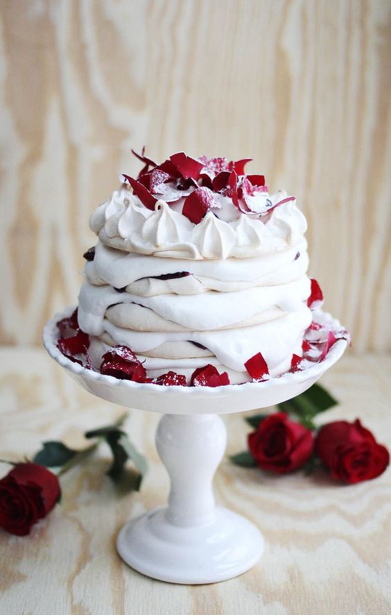 a meringue wedding cake with creamy drip and red petals with sugar on top is a lovely idea for a modern summer wedding