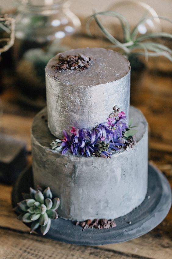 a modern wedding cake with a silver and a grey tier, with purple blooms and succulents is a very stylish idea inspired by concrete