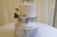 a modern wedding cake with a white glitter, silver leaf and marble tier, with white blooms and a calligraphy topper is a stunning idea