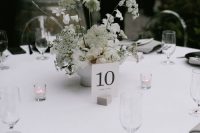 a monochromatic modern wedding tablescape with white blooms, black chargers and cutlery, candles and grey napkins