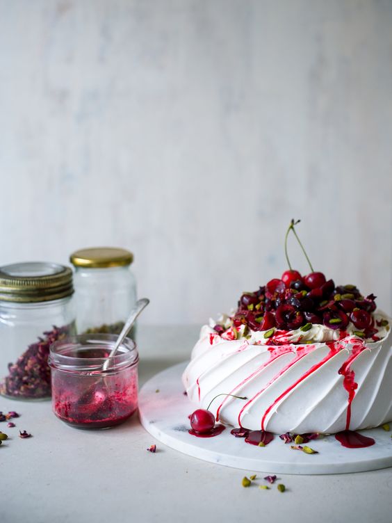 a pavlova wedding cake topped with cherries, cherry drip, pistachios is a delicious idea for a summer or summer to fall wedding