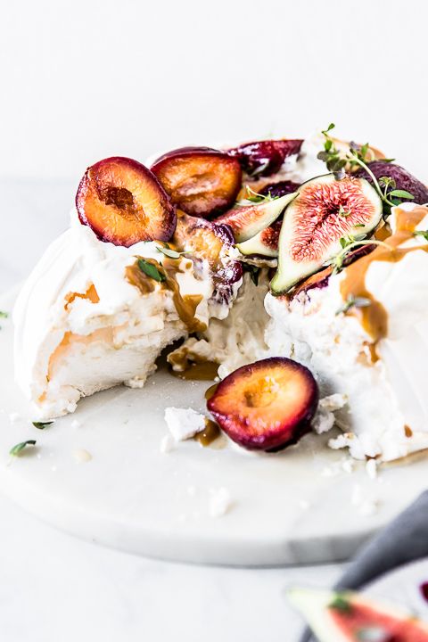 a pavlova wedding cake topped with fresh plums and figs, with greenery and caramel drip is a lovely idea for a summer to fall wedding