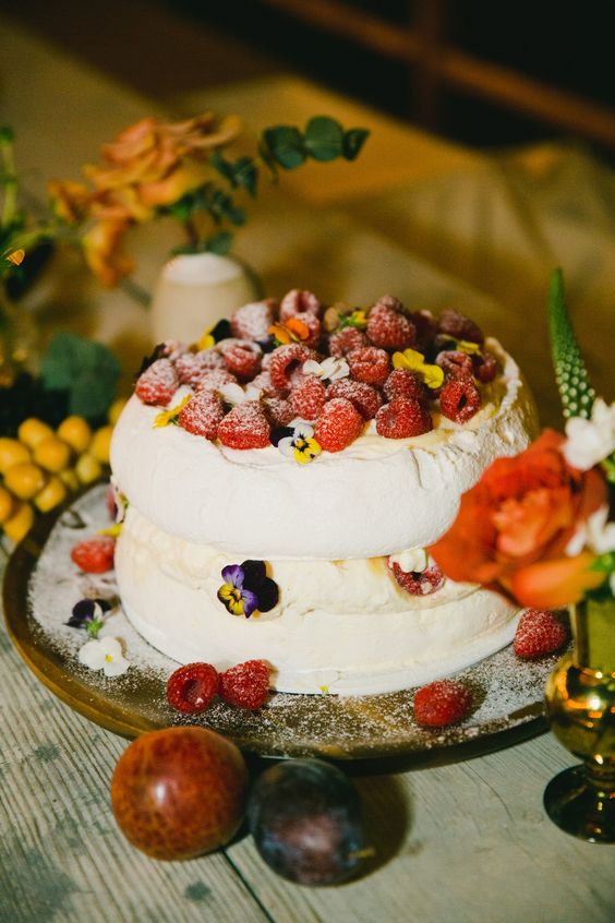 a pavlova wedding cake with berries on top and some bright flowers is a gorgeous idea for a summer wedding