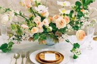 a refined wedding centerpiece composed of white anemones, peachy ranunculus, white blooms and lots of greenery is a stylish dimensional decoration