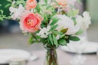 a simple and stylish wedding centerpiece of white peonies and blush ones, bright pink ranunculus, greenery and some fillers is cool