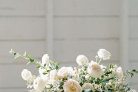 a sophisticated wedding bouquet of white ranunculus, peony roses, greenery, white berries is a lovely idea for a spring or summer wedding