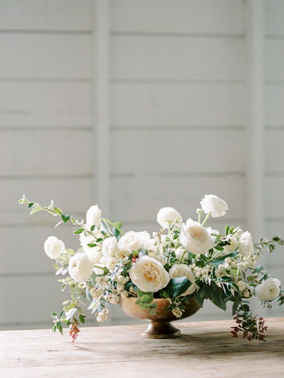 a sophisticated wedding bouquet of white ranunculus, peony roses, greenery, white berries is a lovely idea for a spring or summer wedding