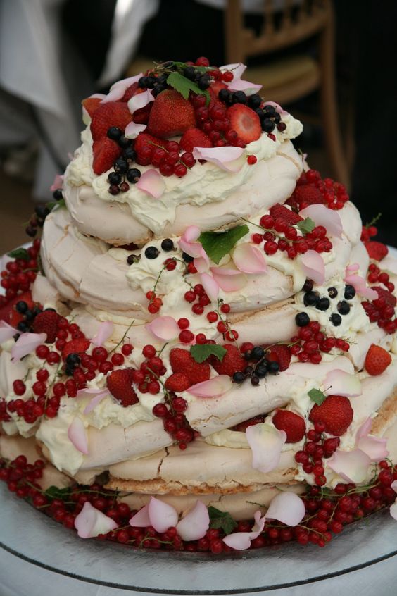 a tiered pavlova wedding cake topped with pink petals and fresh berries of all kinds is a lovely idea for a summer wedding