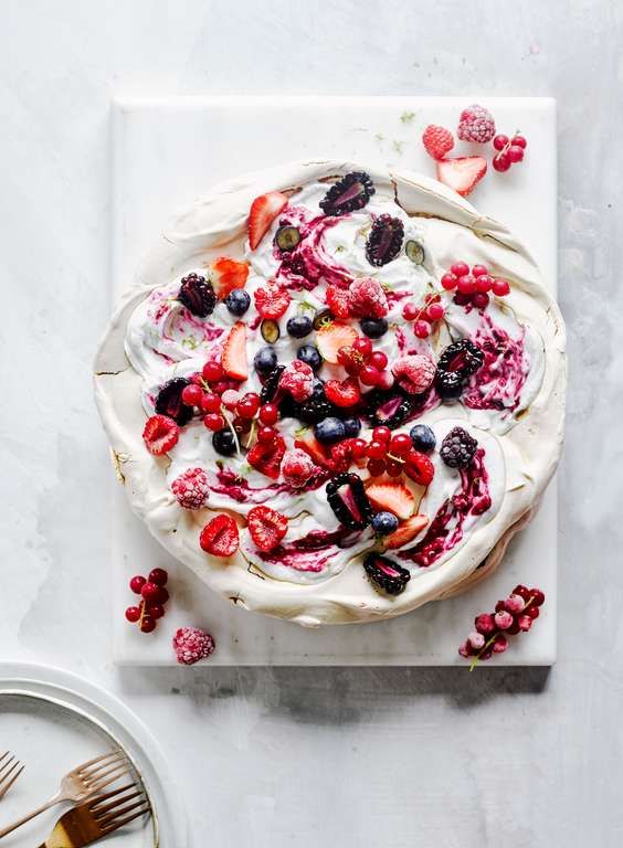 a vegan layered pavlova with coconut cream cleverly uses aquafaba to create the perfect meringue base, topped with fresh fruit