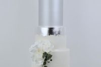 a white wedding cake with white tiers, a matte silver and a silver leaf tier, white blooms and greenery is a very chic idea