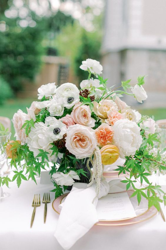 an adorable wedding centerpiece of white peony roses, anemones and ranunculus, peachy peony roses and yellow ranunculus plus lots of greenery