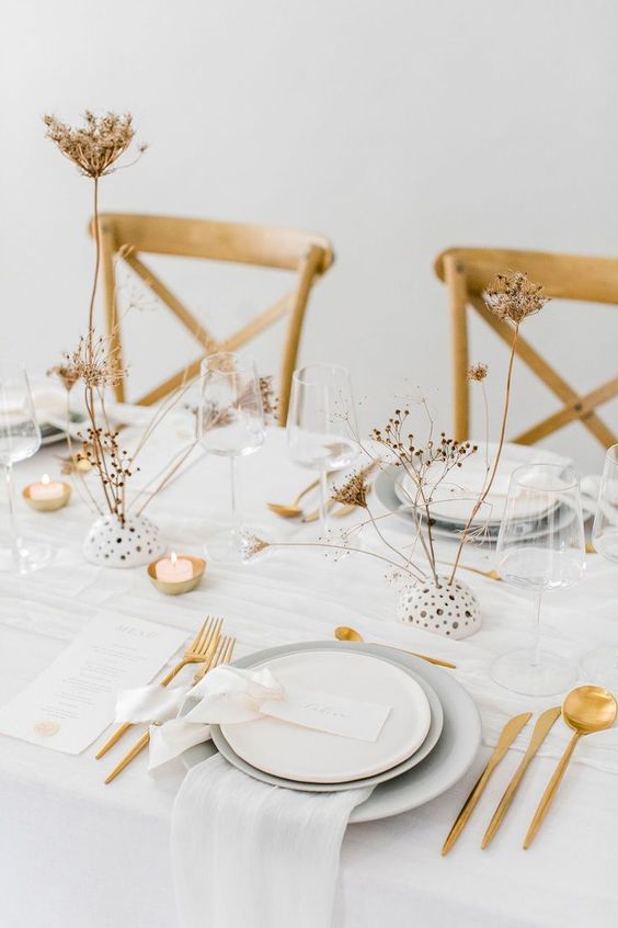 an ethereal neutral wedding tablescape with dried blooms, gold cutlery, grey and white plates and neutral linens is amazing