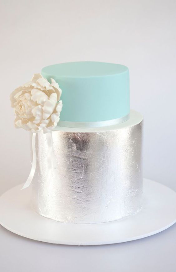 a glam wedding cake with a mint and silver tier plus a white sugar bloom on the side is cool