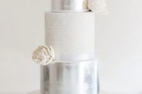 a large vintage-inspired wedding cake with a silver, white patterned and white sleek tier, white sugar blooms is wow